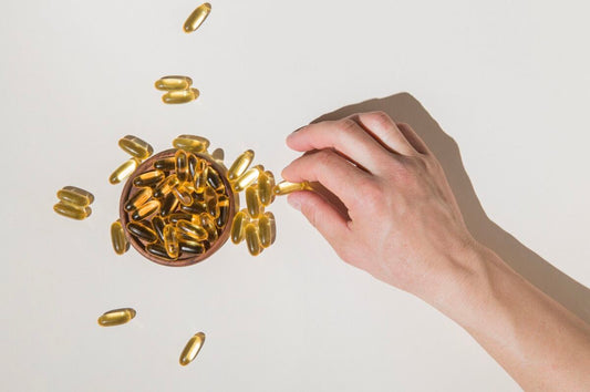 Mão pegando cápsulas de óleo de peixe em recipiente