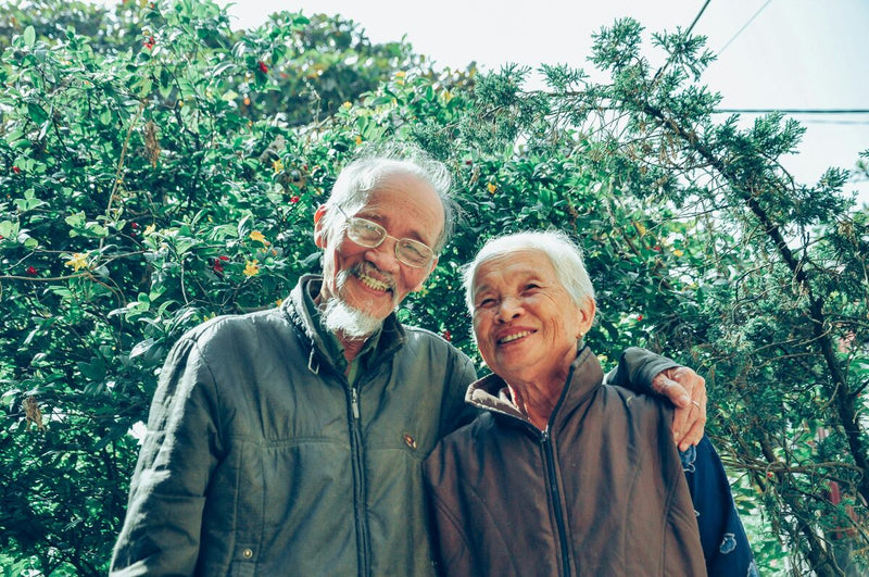 Casal idoso sorrindo em um ambiente verdinho