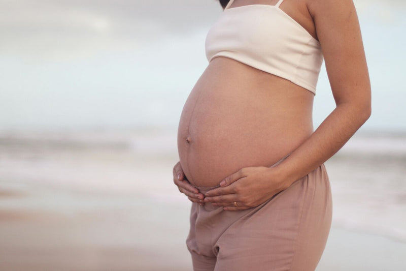 Gestante na praia exibindo a barriga