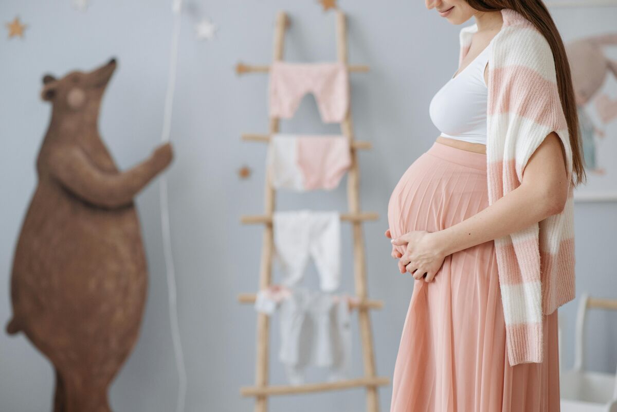 Grávida acariciando a barriga em quarto infantil