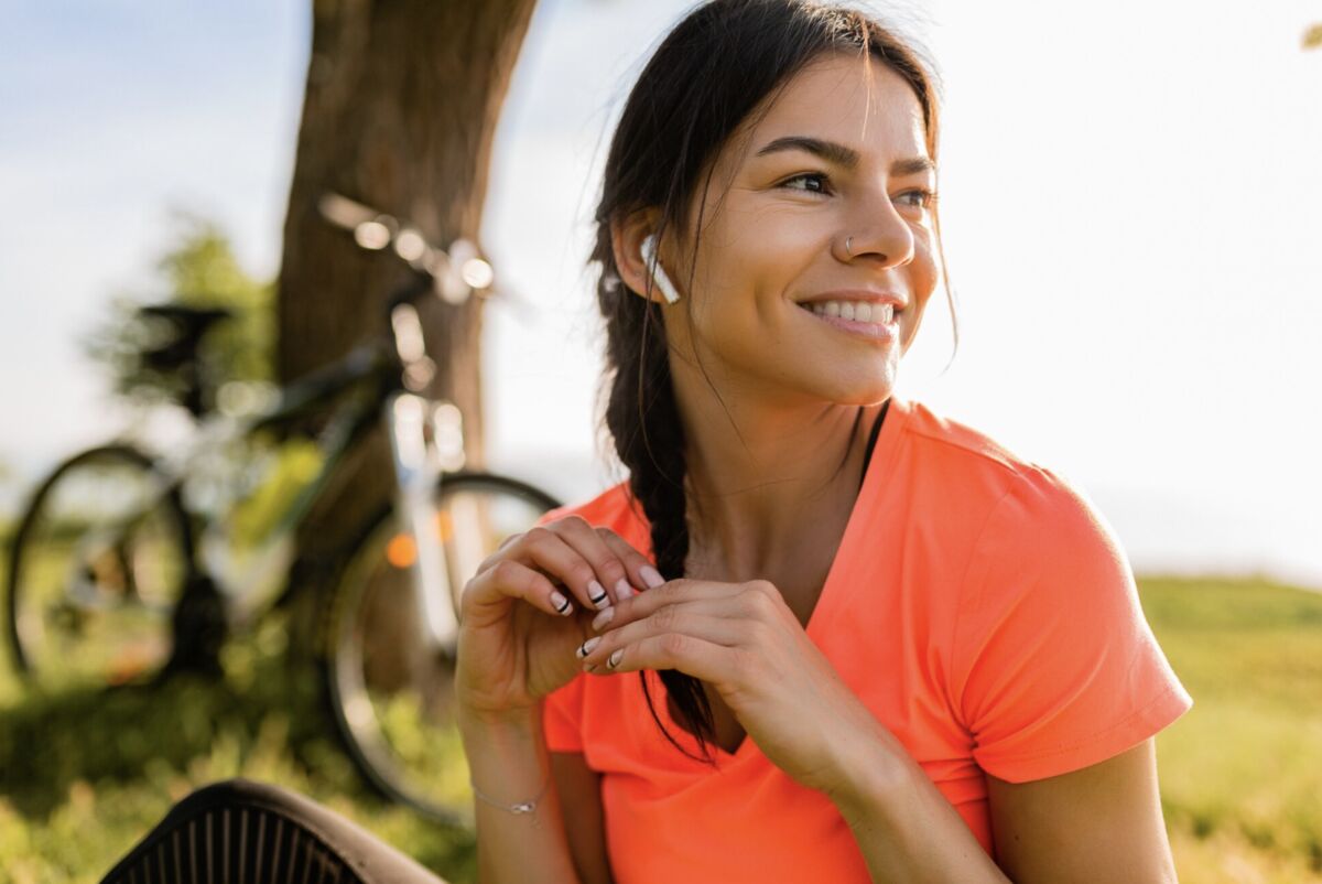 Mulher sorridente usando fones ao ar livre - CoQ10 e vitamina D combinação essencial