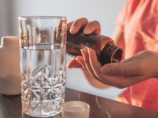 Pessoa segurando frasco com água em copo