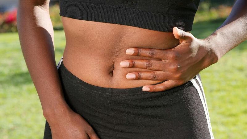 Pessoa com a mão na barriga em ambiente externo